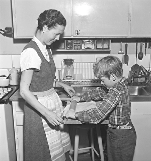 Baking in the 1950s. A mother with her son in the kitchen
