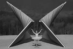 Ballerina in white tutu posing gracefully between modern metal sculptures