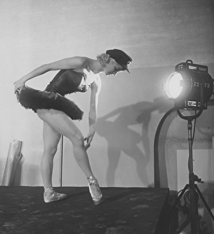 Ballet dancer in the 1950s. A young woman in her stage costume is standing with a spotlight directed at her body