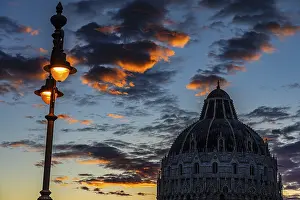 Baptistery chapel under an illuminated street lamp at sunset