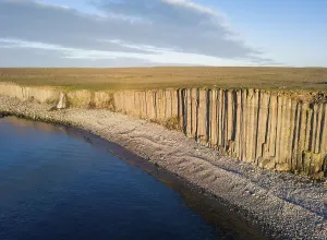 Basalt columns in the evening light at the beach with waterfall