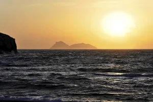 Bay, beach of Matala, sunset over the sea with silhouette of an island on the horizon
