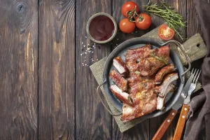 BBQ grilled veal calf brisket meat on short spare rib on plate over rustic wooden table
