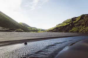 Framed Print : Beach with a flowing river, surrounded by hills and mountains under a blue sky