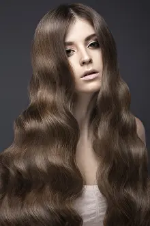 Beautiful brunette girl with a perfectly curls hair and classic make-up