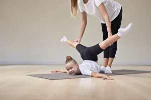 Beautiful female teacher helps a little girl stretch in a gymnastics class. The concept of education, sports, Pilates, stretching, healthy lifestyle