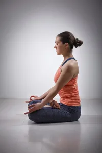 Beautiful fit yogini woman meditating in yoga asana Padmasana (Lotus pose)
