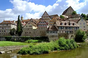 Beautiful half-timbered houses with red roofs in the winding old town of Schwaebisch Hall overlook the river Kocher