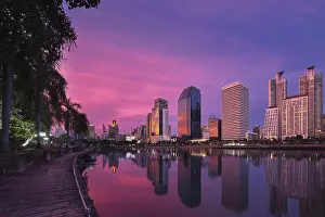 Beautiful landscape with modern high-rise buildings reflecting in calm lake waters by park