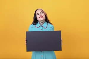 Beautiful woman holding a blank sign against a yellow background