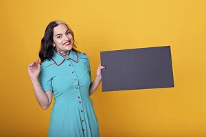 Beautiful woman holding a blank sign against a yellow background