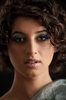 Beautiful young girl with dark curly hair and a make up in peacock colour
