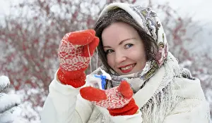 Beautiful young Russian folk woman in winter park with christmas tree toy