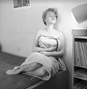 Beauty care in the 1950s. A young woman is getting a tan by the artificial sunlight from the home tanning sunlamp