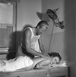 Beauty care in the 1950s. A young woman is having a massage by a man handling the treatment