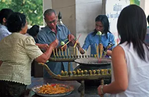 Believers light candles in front of the temple with the Buddha statue Phra Mongkhonbophit