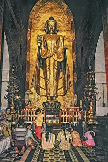 Believers standing in front of a large Buddha in Ananda Temple in Bagan