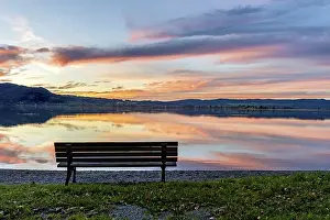 Bench at Lake Kochel, reflection of sun and clouds at sunset