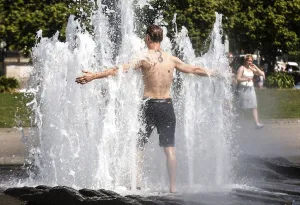 Berlin, 19 July 2022, A man cools off at a fountain in Berlin's Lustgarten