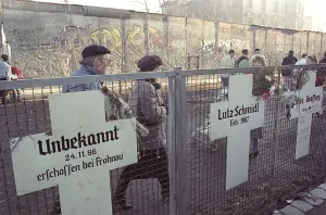 Berlin people passing on the west side of the wall at memorial crosses for victims of the GDR regime