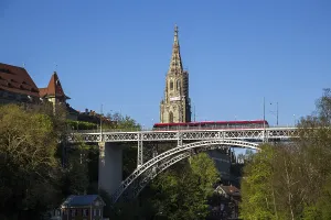 Bern, Switzerland, April 13, 2017: Train driving over Kirchenfeld Bridge with the Cathedral in the background