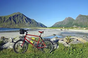A bicycle on the beach with a view of the surrounding mountains and the sea