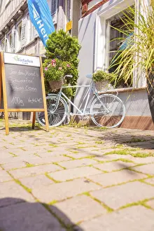 Bicycle with flower baskets and chalkboard in front of a cafe in the sunshine