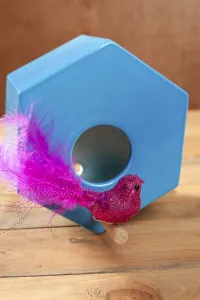 Bird in blue nest house polygonal shape over wood