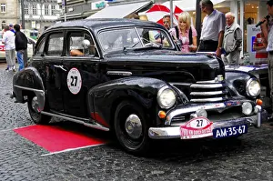 Framed Print : Black classic car in an urban environment at an event with people and rainy weather
