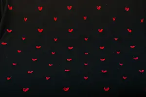 Black fabric background with red hearts shapes