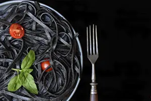 Black pasta coloured with squid ink and fork