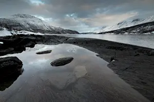 Black rocky coast in a bay in the Ullsfjord