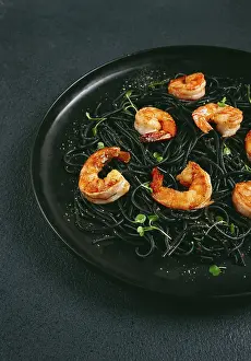 Black spaghetti with shrimp, on a black plate