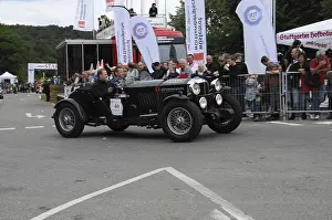 A black vintage car drives past spectators at a racing event