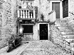 Black and white picture of a Vespa in an old-fashioned alley