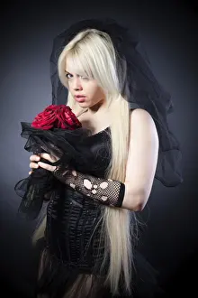 Black widow in grief with flowers with a veil on a black background