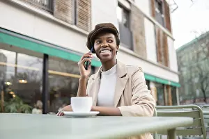 Black woman sits at an outdoor cafe
