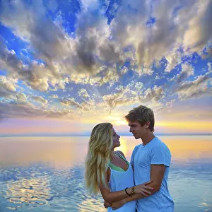 Blond young couple hug in sunset sea lake happy together