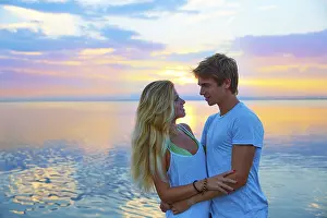 Blond young couple hug in sunset sea lake happy together