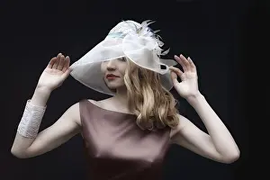 Blonde girl in silk dress with basque touching fashionable wide brim hat