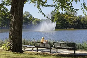 Blonde woman on park bench looking at fountain in Knieperteich Stralsund