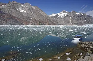 Blue boat in a calm fjord covered with pieces of ice