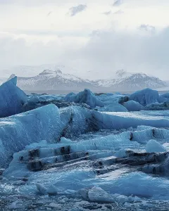 Blue glaciers stretch across the landscape with mountains in the distance