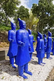 Several blue terracotta soldier statues stand on gravel