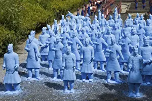 Many blue terracotta warrior statues stand on a path and appear to be in formation