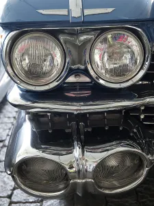 Blue vintage car with double headlights and shiny chrome details in retro style