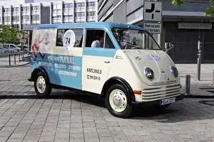 Blue and white vintage van with advertising lettering and number 74 on cobblestones