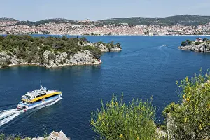 A boat sails through the clear blue water with a view of a town