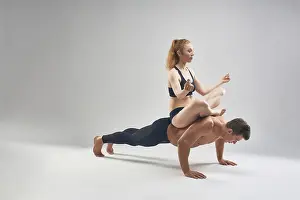 Full body of focused strong shirtless male athlete doing push ups with female partner sitting on back