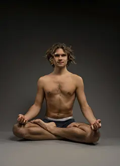 Full body shirtless young man in boxer briefs sitting in Lotus pose